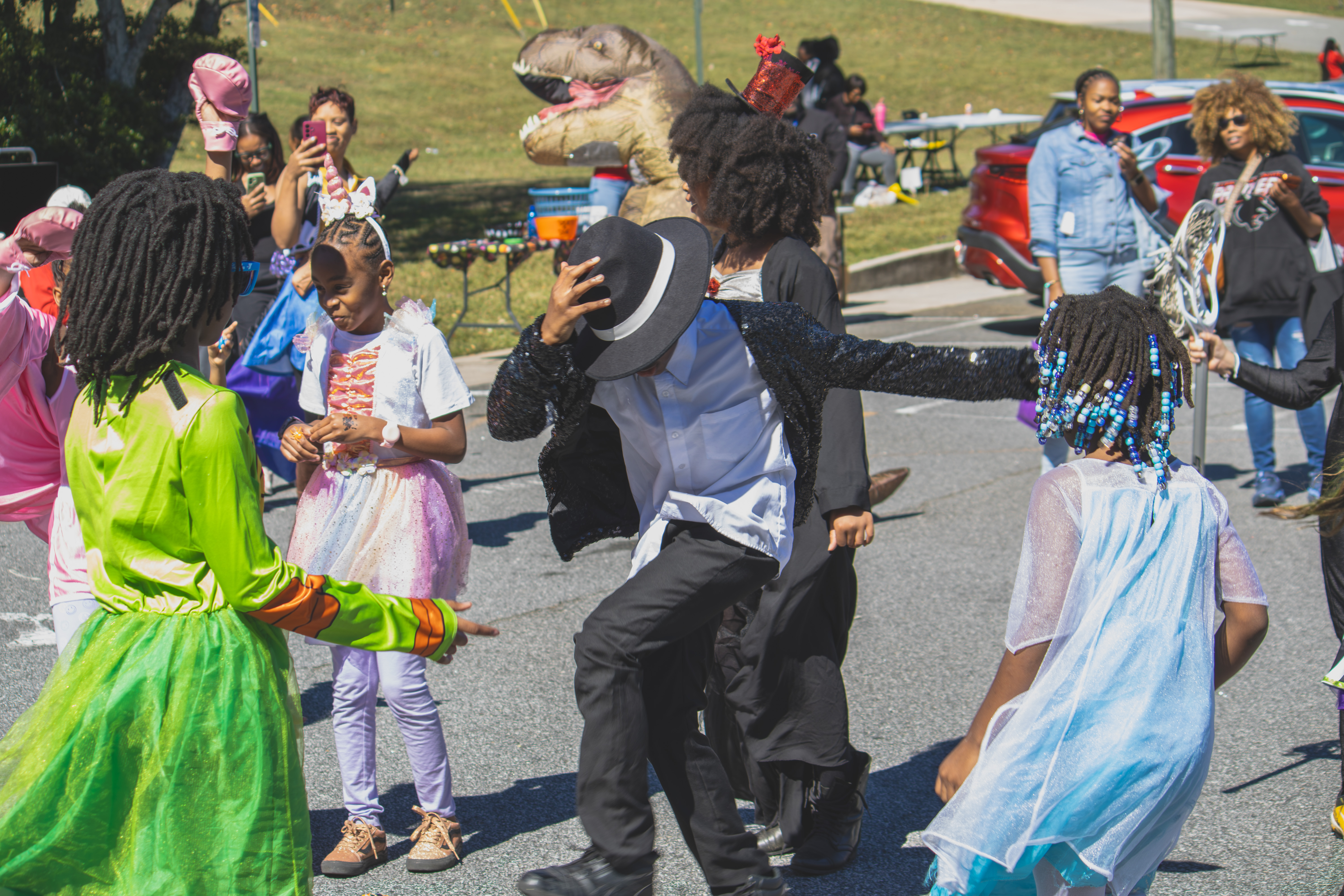 Children dance in costume, including a dancer in a black sequined jacket and fedora.