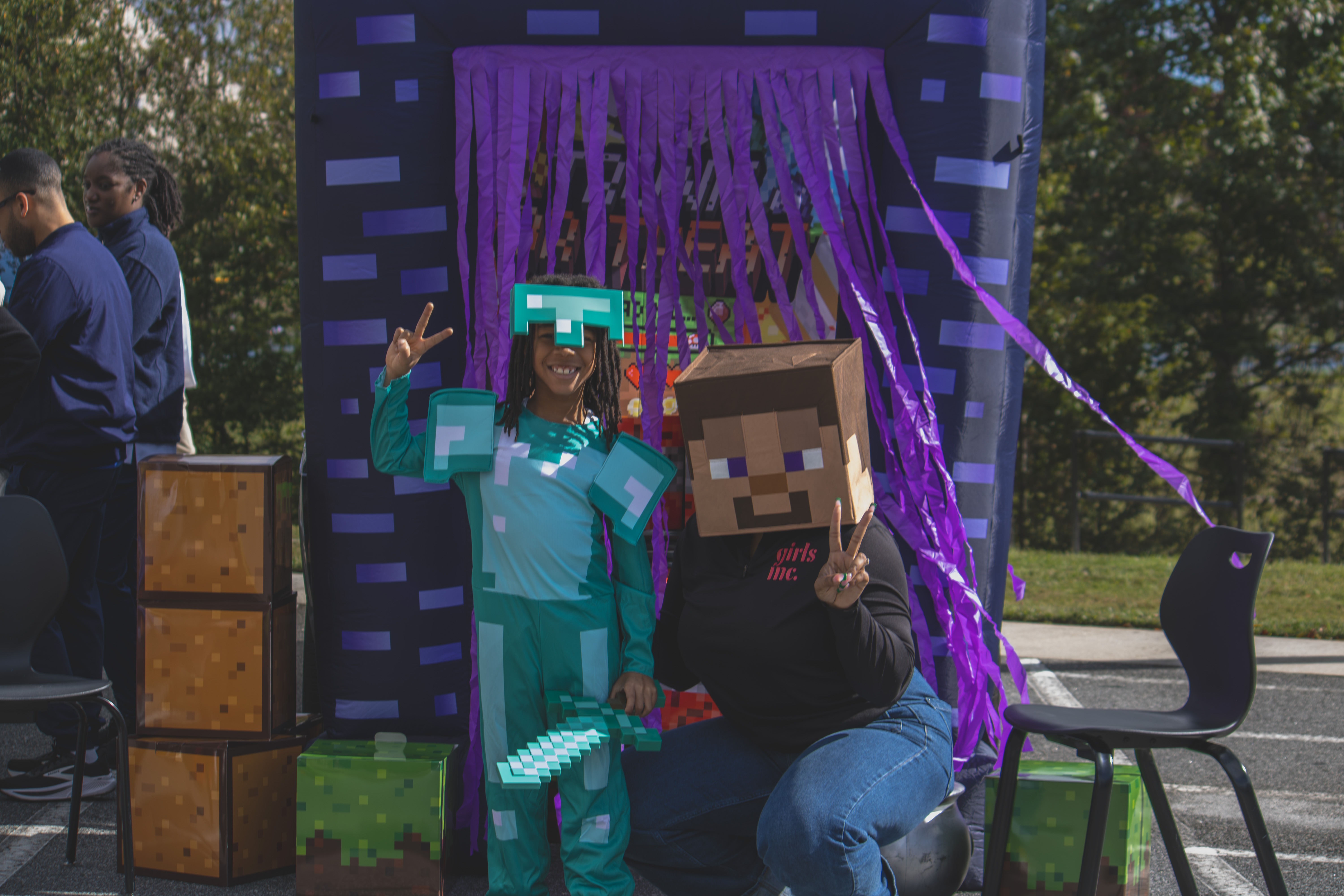 Two participants in Minecraft-inspired costumes pose in front of a purple portal display.
